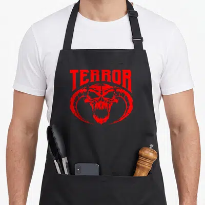 Tablier de cuisine noir avec un crâne démoniaque rouge et le mot TERROR imprimé en typographie agressive.
