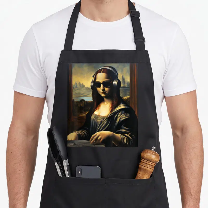 Tablier de cuisine noir avec une illustration de la Mona Lisa en DJ portant des écouteurs et des lunettes noires devant un paysage fantastique.