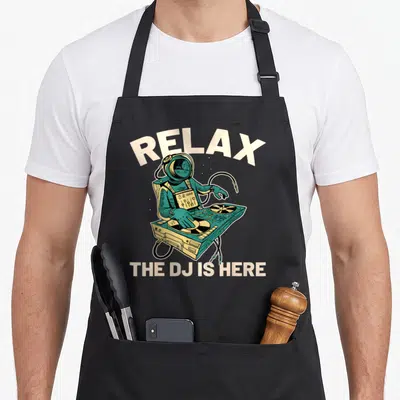 Tablier de cuisine noir avec illustration d'un astronaute DJ et texte Relax The DJ is Here en beige.
