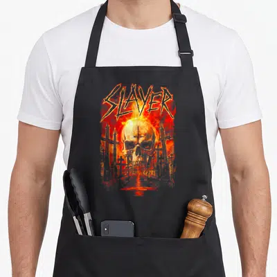 Tablier de cuisine noir avec un crâne enflammé et le mot Slayer au-dessus d'un cimetière.