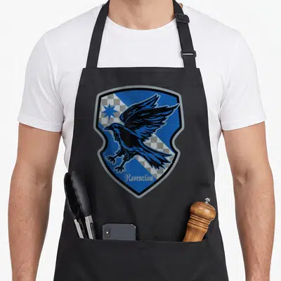 Tablier de cuisine noir avec un grand blason bleu affichant un corbeau et l'inscription Ravenclaw en bas.