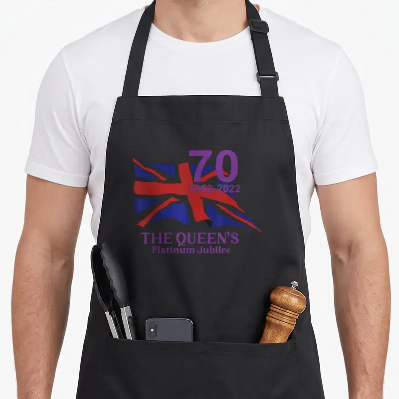 Tablier de cuisine noir avec drapeau britannique stylisé et texte 70 The Queen's Platinum Jubilee en violet.