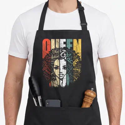 Tablier de cuisine noir avec illustration stylisée Queen Strong Black Woman en lettres colorées et portrait féminin.