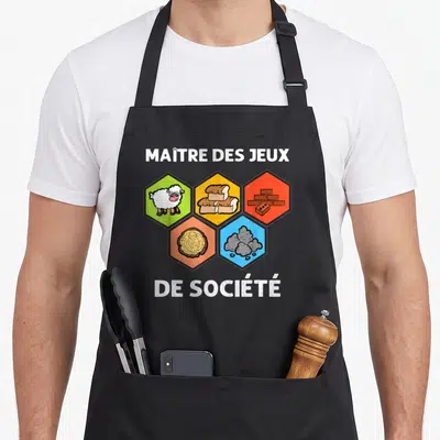 Tablier de cuisine noir avec texte Maître des jeux de société et cinq hexagones colorés représentant des ressources de jeu.