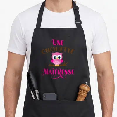Tablier de cuisine noir avec une chouette maîtresse imprimée en rose et marron sur une branche.
