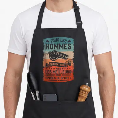 Tablier de cuisine noir avec motif vintage coloré représentant un sifflet de coach et une phrase humoristique sur les professeurs de sport.