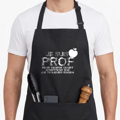 Tablier de cuisine noir avec inscription blanche Je suis prof et une illustration de pomme à côté du texte.