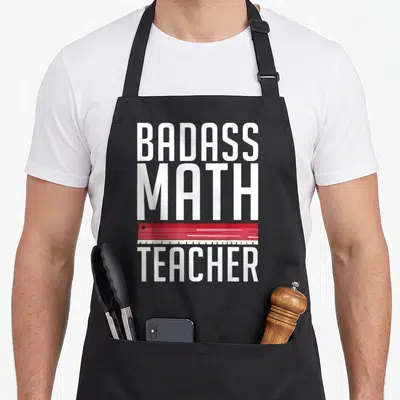 Tablier de cuisine noir avec l'inscription Badass Math Teacher et une illustration de règle rouge en travers du texte blanc.