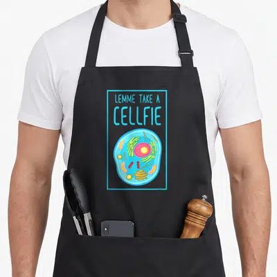 Tablier de cuisine noir avec illustration colorée d'une cellule biologique et le texte LEMME TAKE A CELLFIE en lettres capitales bleues.