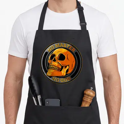 Tablier de cuisine noir avec un crâne orange circulaire portant les textes No Master et No God en lettres jaunes.