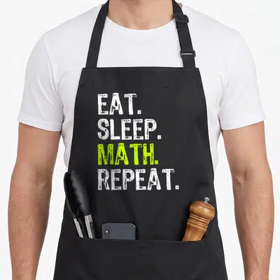 Tablier de cuisine noir avec le texte Eat Sleep Math Repeat en lettres blanches et vertes sur fond uni.