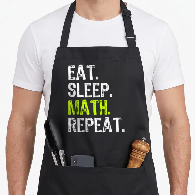 Tablier de cuisine noir avec le texte Eat Sleep Math Repeat en lettres blanches et vertes sur fond uni.
