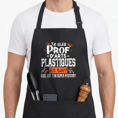 Tablier de cuisine noir avec inscription Je suis prof d'arts plastiques et quel est ton super pouvoir en typographie blanche et orange.