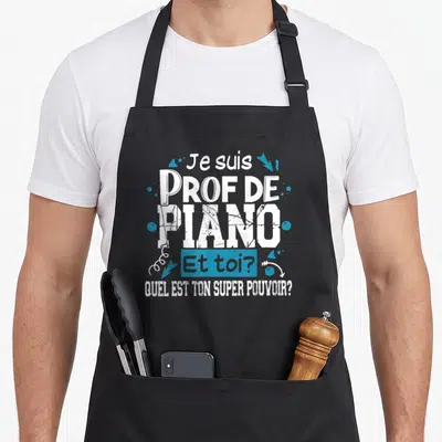 Tablier de cuisine noir avec le texte Je suis prof de piano et toi quel est ton super pouvoir en blanc et bleu.