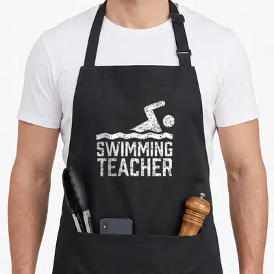 Tablier de cuisine noir avec illustration blanche d'un nageur et le texte Swimming Teacher en typographie usée.