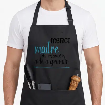 Tablier de cuisine noir avec l'inscription Merci maître de m'avoir aidé à grandir en typographie noire et bleue.