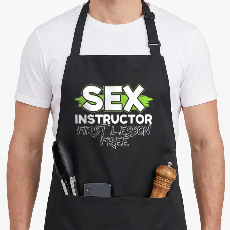 Tablier de cuisine noir avec le texte Sex Instructor First Lesson Free en blanc et vert lime.
