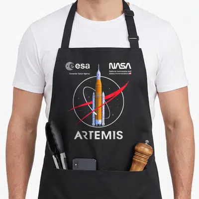 Tablier de cuisine noir avec illustration du lanceur Artemis SLS, logos NASA et ESA, et le mot ARTEMIS en bas.