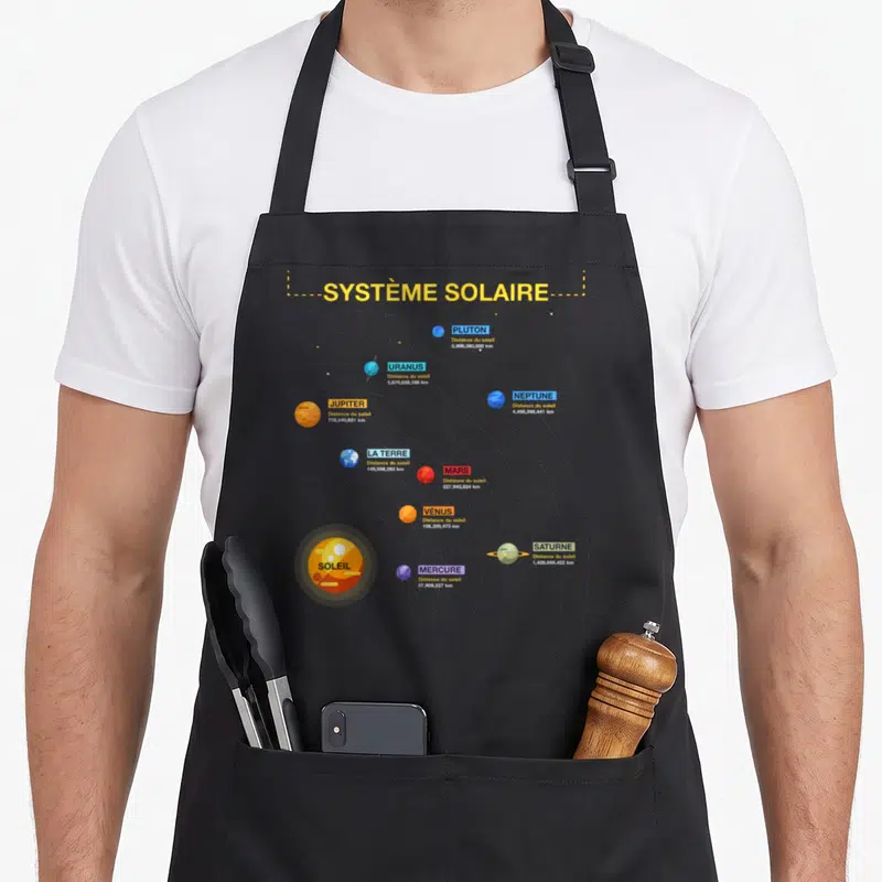 Tablier de cuisine noir avec une illustration colorée du Système Solaire montrant les planètes et leurs distances en kilomètres.