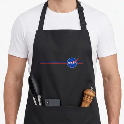 Tablier de cuisine noir avec le logo NASA bleu blanc et rouge traversé par deux bandes horizontales parallèles.