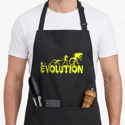 Tablier de cuisine noir avec motif jaune Evolution et silhouettes d'aliens évoluant depuis une planète jusqu'à une créature monstrueuse.