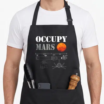 Tablier de cuisine noir avec inscription Occupy Mars, planète orange et dessin technique blanc de vaisseau spatial.