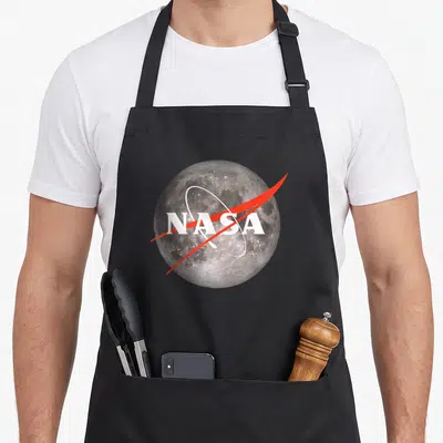 Tablier de cuisine noir avec une lune texturée et le logo NASA traversé par une ligne rouge.