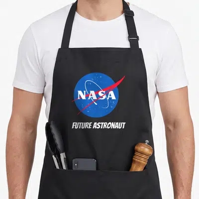 Tablier de cuisine noir avec un logo circulaire bleu portant les mots NASA et Future Astronaut souligné par une ligne rouge diagonale.