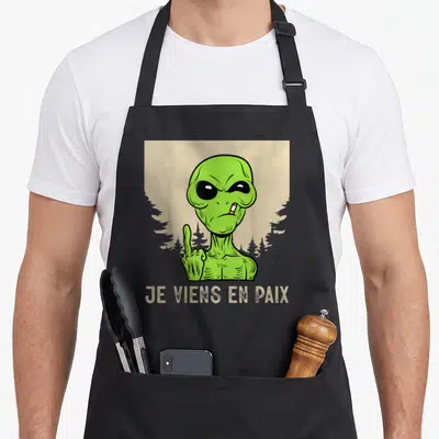 Tablier de cuisine noir avec un alien vert fumant et l'inscription Je viens en paix en bas.