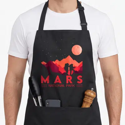 Tablier de cuisine noir avec illustration du Mars National Park montrant des montagnes rouges et une planète orbitale dans un ciel étoilé.