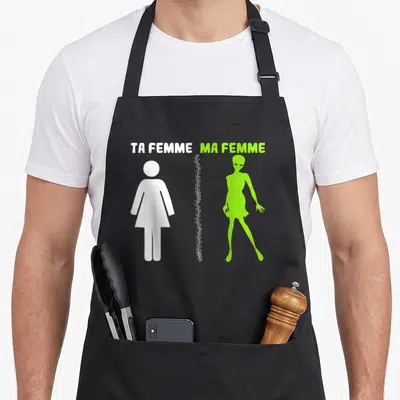 Tablier de cuisine noir avec silhouette humaine blanche et alien vert fluorescent sous les mots ta femme ma femme.