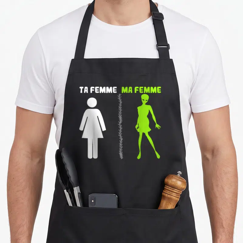 Tablier de cuisine noir avec silhouette humaine blanche et alien vert fluorescent sous les mots ta femme ma femme.