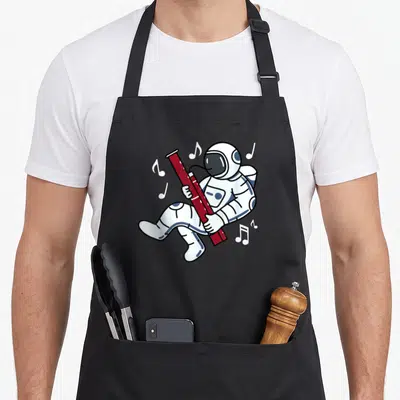 Tablier de cuisine noir avec un astronaute flottant jouant d'un basson rouge entouré de notes de musique blanches.