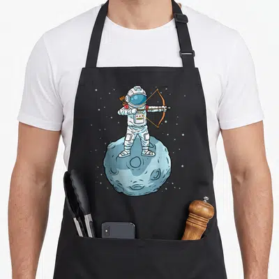 Tablier de cuisine noir avec illustration d'un astronaute tirant à l'arc sur une surface lunaire étoilée.