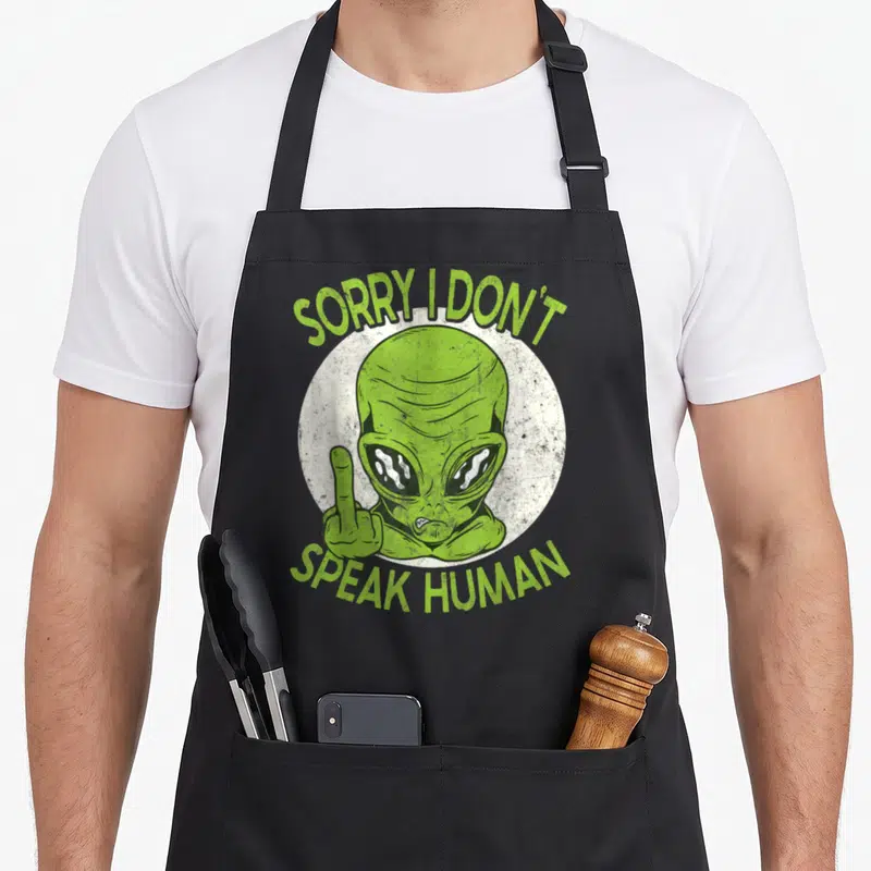 Tablier de cuisine noir avec un alien vert levant le majeur et le texte sorry i don t speak human.