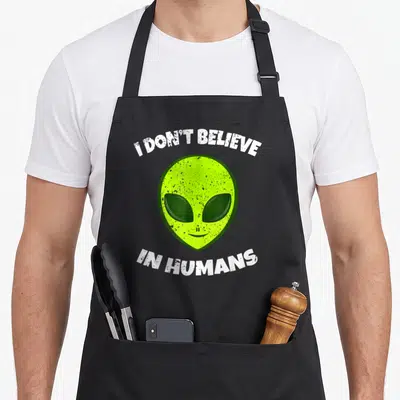 Tablier de cuisine noir avec tête d'alien verte et texte blanc délavé I DON'T BELIEVE IN HUMANS.