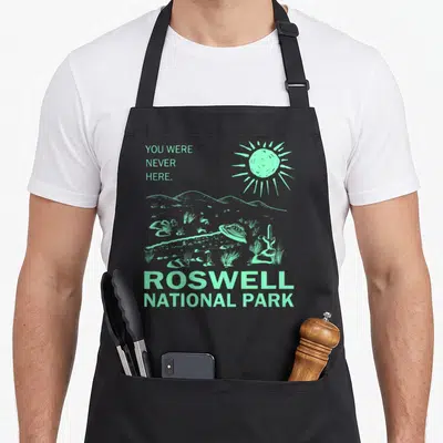 Tablier de cuisine noir avec illustration d'un désert et d'une soucoupe volante en vert menthol.