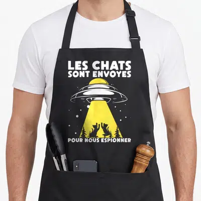 Tablier de cuisine noir avec vaisseau spatial jaune et texte Les chats sont envoyés pour nous espionner.