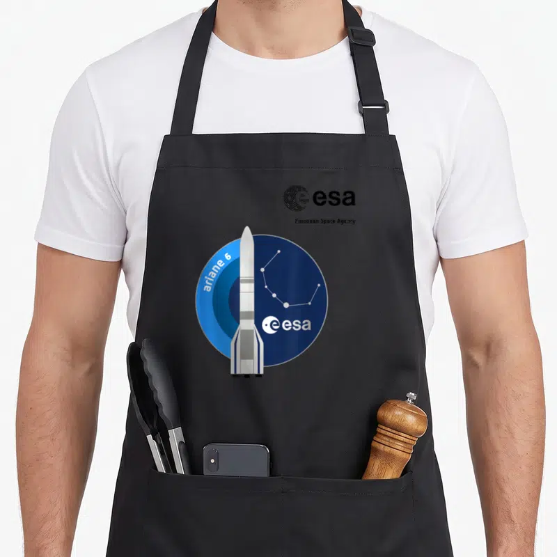 Tablier de cuisine noir avec illustration de la fusée Ariane 6 et le logo de l'ESA sur un cercle bleu.