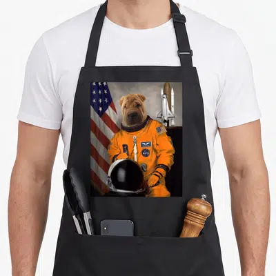 Tablier de cuisine noir avec illustration d'un chien Shar-Pei vêtu d'une combinaison spatiale orange.