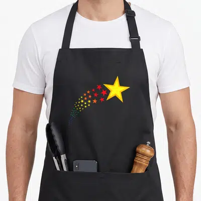 Tablier de cuisine noir avec une grande étoile jaune et une traînée d'étoiles multicolores en forme d'arc.