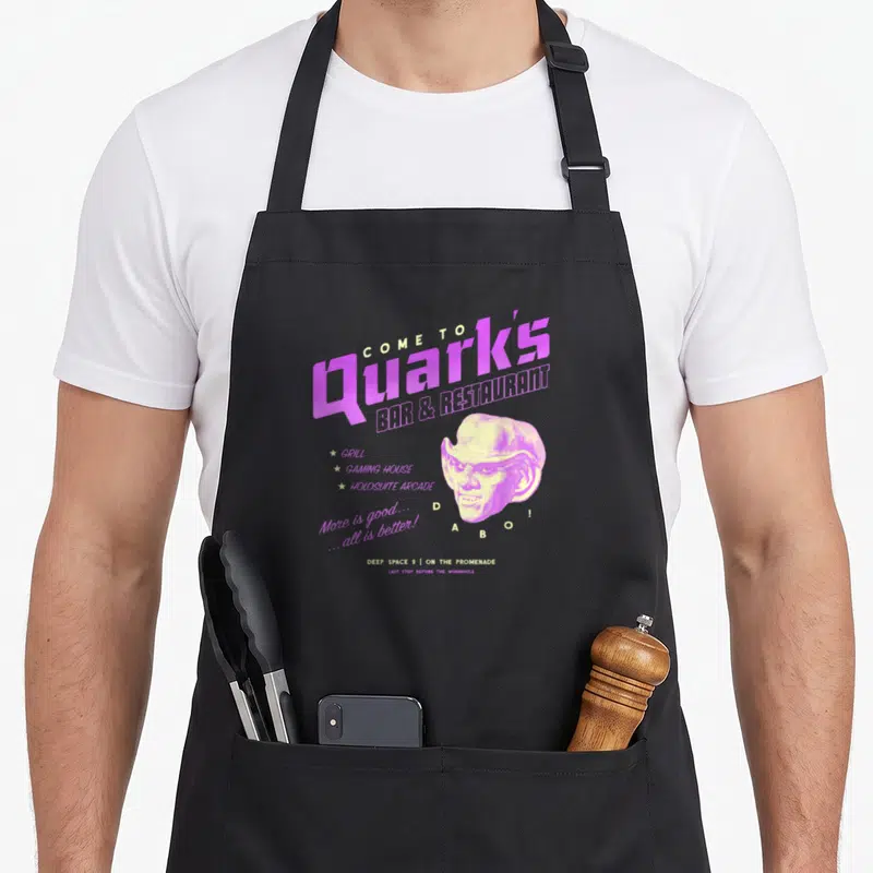 Tablier de cuisine noir avec logo vintage Quarks Bar Restaurant illustration Dabo et texte Deep Space 9 en violet et jaune