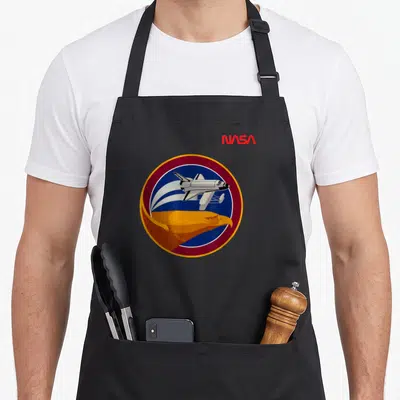 Tablier de cuisine noir avec l'emblème circulaire de la mission STS 51 G montrant une navette et un aigle doré.