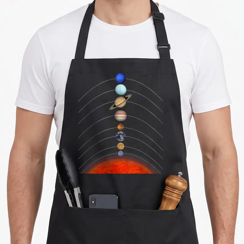 Tablier de cuisine noir avec illustration du système solaire montrant le Soleil et les planètes alignées verticalement.
