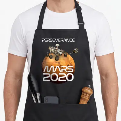 Tablier de cuisine noir avec illustration du rover Perseverance posé sur une représentation de la planète Mars en orange.