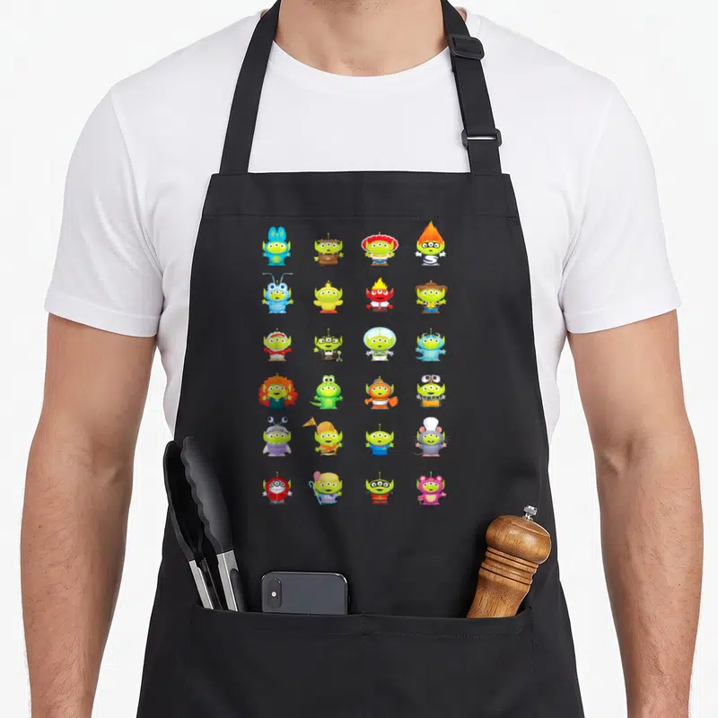 Tablier de cuisine noir avec une grille d'aliens verts de Toy Story déguisés en divers personnages de fiction colorés.