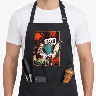 Tablier de cuisine noir avec un astronaute tenant le doigt et disant taxi.