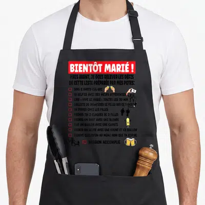 Tablier de cuisine noir avec liste de défis drôles et illustrations pour enterrement de vie de garçon.