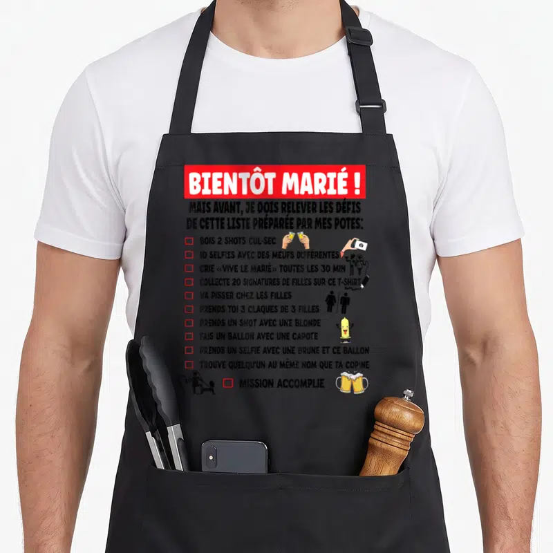Tablier de cuisine noir avec liste de défis drôles et illustrations pour enterrement de vie de garçon.