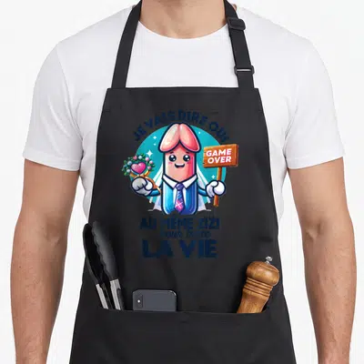 Tablier de cuisine noir avec illustration cartoon d'un personnage en costume tenant une bague et une pancarte Game Over.